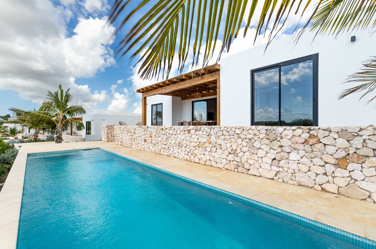 Infinity pool langs de villa met tropische tuin